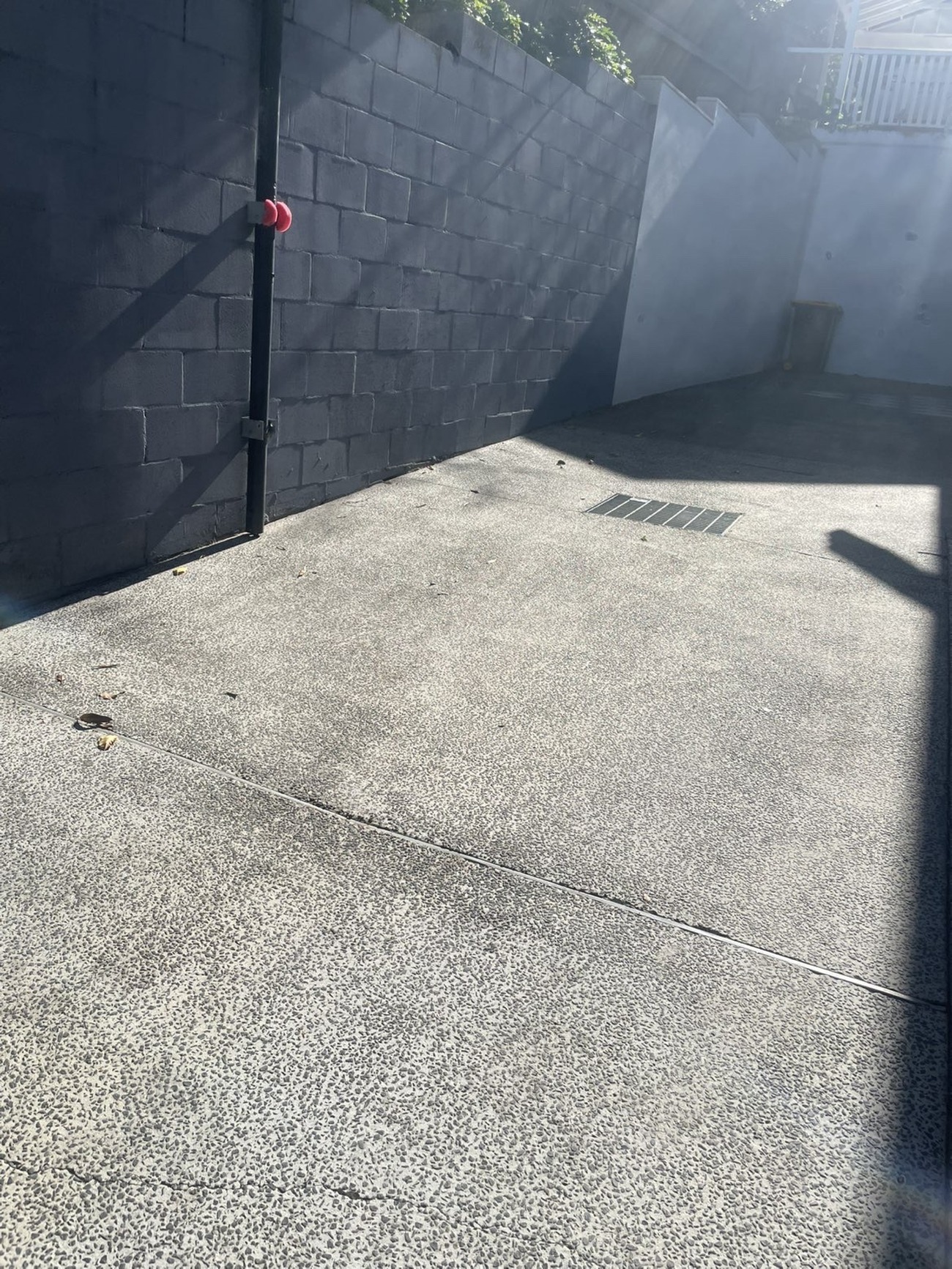 Clean exposed aggregate driveway beside a rendered block wall, bright and free of stains.