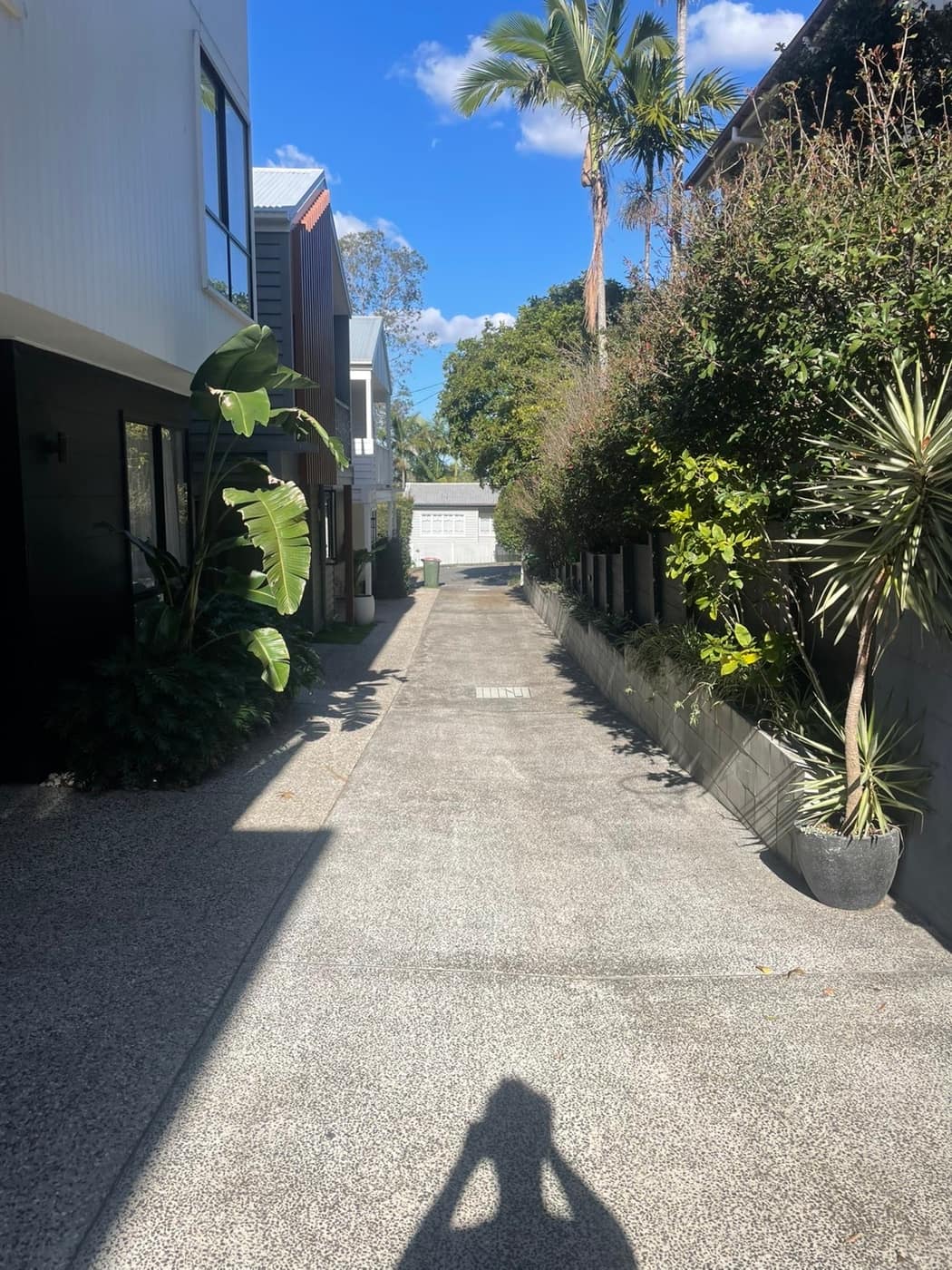 Long exposed aggregate driveway between townhouses, freshly cleaned on a sunny Brisbane day.